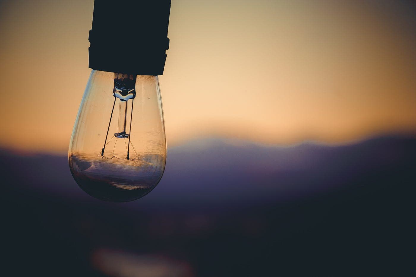 unlit lightbulb with blurred yellow sunset background